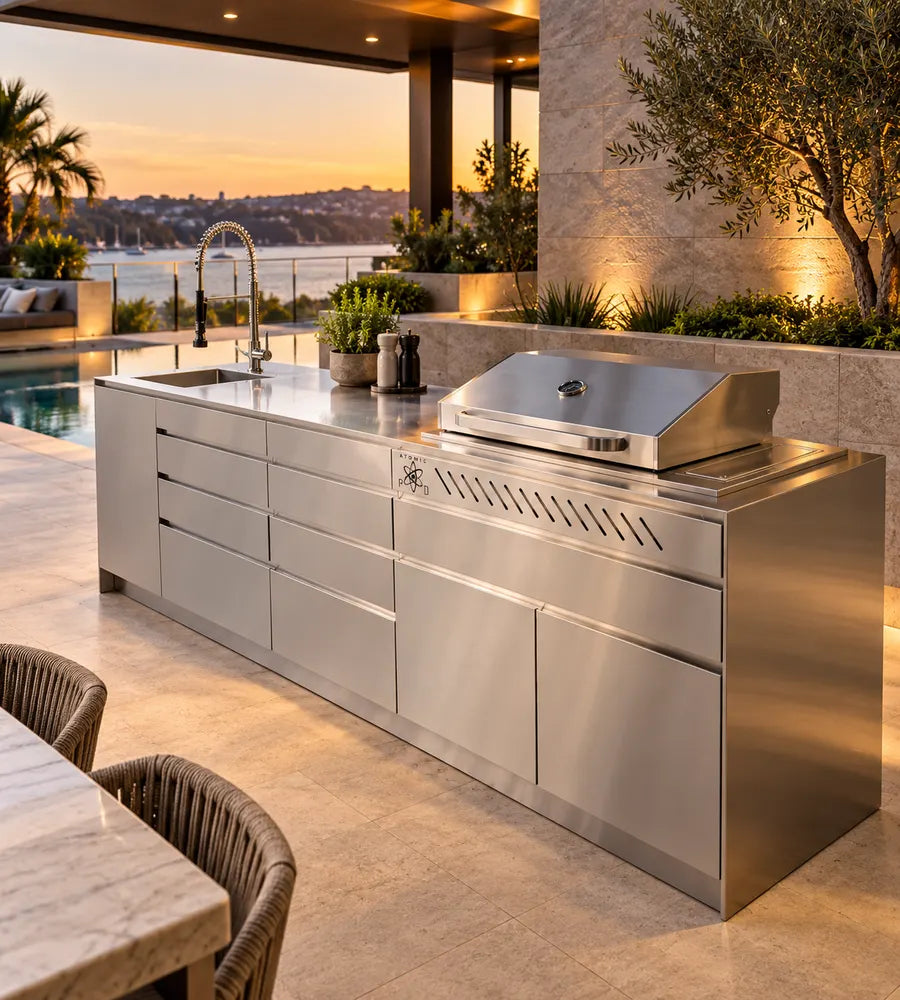 Brushed stainless steel outdoor kitchen with built-in BBQ, sink and drawers beside a pool